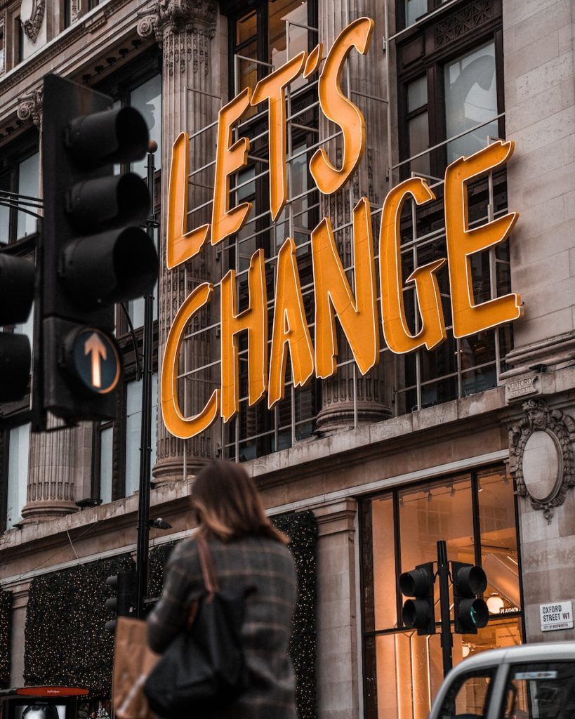 a woman walking past a building with a sign that says let's change