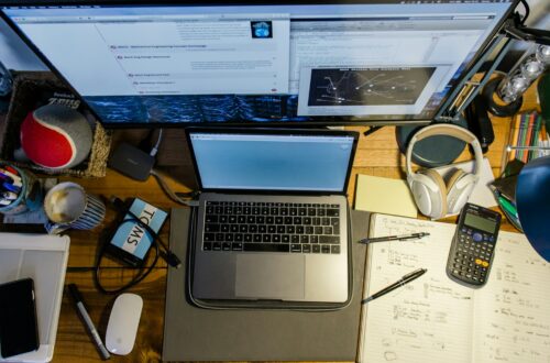 high-angle photography of laptop near calculator, pens, and mouse